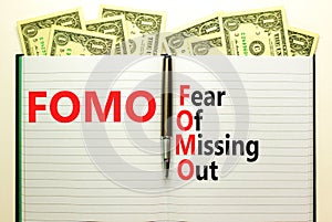 FOMO fear of missing out symbol. Concept words FOMO fear of missing out on book on beautiful white background. Dollar bills.