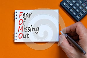 FOMO fear of missing out symbol. Concept words FOMO fear of missing out on the note on a beautiful orange background. Businessman