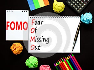 FOMO fear of missing out symbol. Concept words FOMO fear of missing out on white note on a beautiful black background. Black