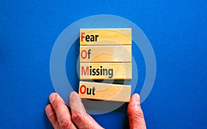 FOMO fear of missing out symbol. Concept words FOMO fear of missing out on wooden blocks on a beautiful blue background.