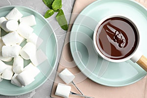 Fondue pot with dark  and marshmallows on table, flat lay