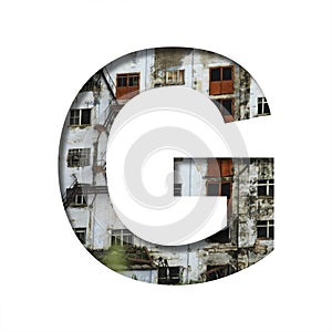 Font on an abandoned industrial building. The letter G cut out of paper on a background of windows and doors of an abandoned