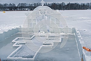 Font for dipping into an ice hole for the baptism of christ and ice sculpture in the form of an angel and a cross