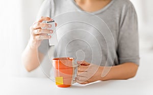 Close up of woman adding sweetener to cup of tea