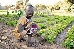 Food for Africa! Young Black Boy Smiling in front of Lettuce Salad Field