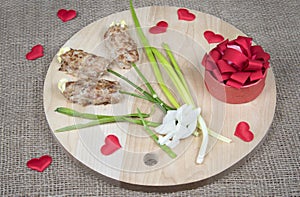 Food art idea for Valentine day, birthday, motherâ€™s day. Flowers made of meat on wooden cutting board, red hearts and natural