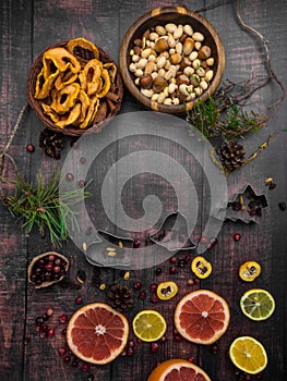 Food background with christmas spices, dried apples, nuts, citrus fruits, cydonia, cranberries, raisin, and baking dish on wooden