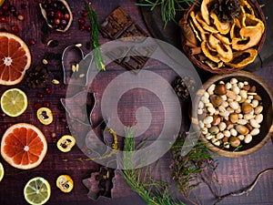 Food background with christmas spices, dried apples, nuts, citrus fruits, cydonia, cranberries, raisin, and baking dish on wooden