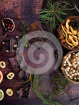 Food background with christmas spices, dried apples, nuts, citrus fruits, cydonia, cranberries, raisin, and baking dish on wooden