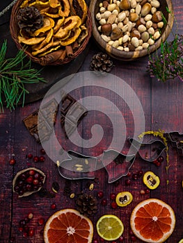 Food background with christmas spices, dried apples, nuts, citrus fruits, cydonia, cranberries, raisin, and baking dish on wooden