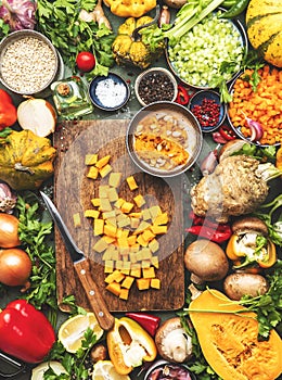 Food background. Diced raw peeled pumpkin and vegetable knife on rustic wooden cutting board. Vegetables, mushrooms, roots, spices