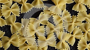 Food background - dry farfalle pasta on black background, uncooked ingredient