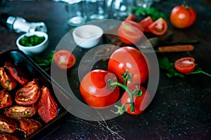 Food background: fresh ripe tomatoes, wooden Board, fresh herbs and spices on a dark background.