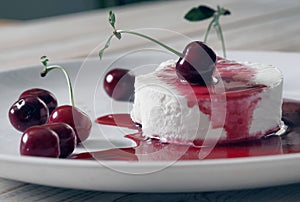 Food background.Ice cream with cherries on a white plate, poured with red jam.Side view.