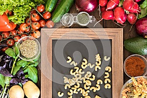 Food background with natural vegetables, spices and two types of Italian pasta on chalkboard