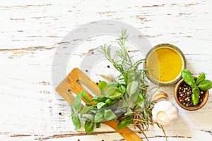 Food background. Olive oil, garlic and herbs on a white wooden table. Top view flat lay background.