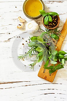 Food background. Olive oil, garlic and herbs on a white wooden table. Top view flat lay background.