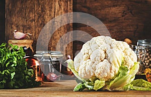 Food background with organic farm cauliflower, pumpkins, herbs and spices on rustic wood kitchen table with spice grinders, herbs