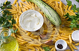 Food background. Penne pasta, zucchini, cream cheese, olive oil, parsley, garlic, salt and black pepper, top view