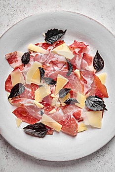 Food background prosciutto coppa di parma ham slices with parmesan cheese and dark basil