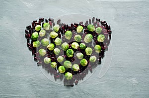 Food background of purple beans and Brussels sprouts in the shape of heart, top view, copy space, closeup.n