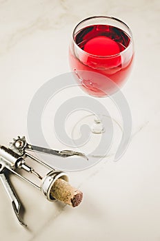 Food background with red Wine glass and corkscrew/red Wine glass and corkscrew on a white marble background. Top view