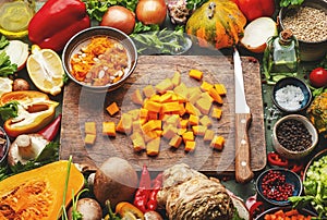 Food background. Sliced pumpkin and knife on cutting board. Vegetables, mushrooms, roots, spices - ingredients for vegan, cooking