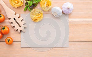 Food background for tasty Italian dishes with blank brown paper and vintage pasta ladle on wooden background. Top view italian