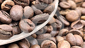 Food background texture of roasted coffee beans with a full shovel. A pile of scattered aromatic roasted brown coffee