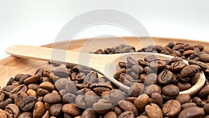 Food background texture of roasted coffee beans with a full shovel. A pile of scattered aromatic roasted brown coffee