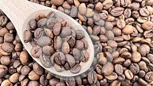 Food background texture of roasted coffee beans with a full shovel. A pile of scattered aromatic roasted brown coffee