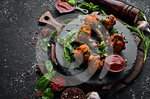 Food. Baked Buffalo Chicken Wings with Ketchup and Balsamic Sauce on a Black Stone Plate. Top view.