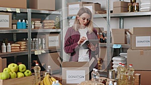 Food bank worker using tablet while packing boxes