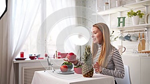 Food blogger cooking fresh vegan salad of fruits in kitchen studio, filming tutorial on camera for video channel. Female