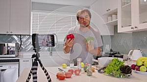 Food blogger cooking meal and recording video for blog. Young cook looking at camera filming himself on smartphone for