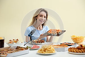 Food blogger eating in front of microphone at table against light background. Mukbang vlog