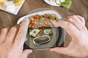 Food blogger using smartphone taking photo .Mans hands make phone photography of  traditional meals.
