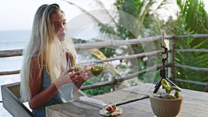 Food blogger woman films video about green salad bowl, dieting for fit skinny body at cafe, sea view. Travel influencer