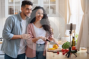 Food Bloggers. Young Arab Couple Recording Video While Cooking In Kitchen