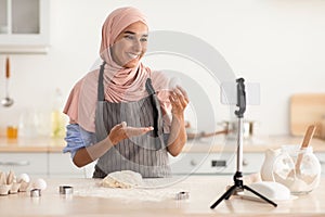 Food Blogging. Beautiful Muslim Lady In Hijab Baking On Camera In Kitchen