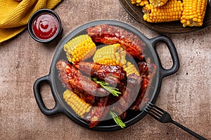 Food board with baked pork ribs with corn cobs, barbecue sauce, rosemary.