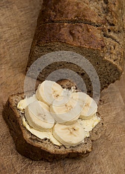 Food : Close up of a sliced, homemade banana loaf cake on a wooden board. 3