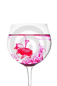 Food coloring diffuse in water inside wine glass area for slogan or advertising text message, on white background.