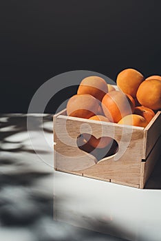 food composition with apricots in wooden box with heart shaped sign on light surface