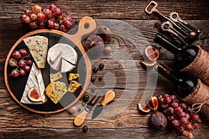 Food composition with assorted cheese, glass of wine and fruits on a wooden table. banner, catering menu recipe place for text,