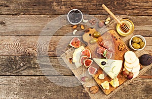 Food composition with cheese plate with cheese, dry meats, various fruits and nuts. Overhead of set of pieces moldy