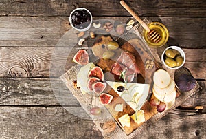 Food composition with cheese plate with cheese, dry meats, various fruits and nuts. Overhead of set of pieces moldy