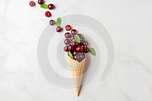 Food composition. Fresh summer cherry berries with mint in waffle ice cream cone on white background. top view