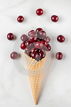 Food composition. Fresh summer cherry berries in waffle ice cream cone on white background. top view. flat lay