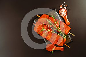 Food concept.Chicken breast Fillets.Fresh raw marinated chicken fillet skewers with fresh herbs on a black background